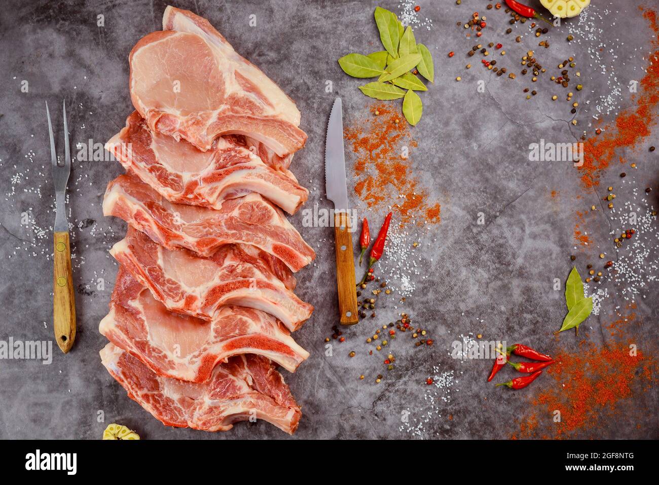 Raw pork chops bone in with spices on dark background. Stock Photo