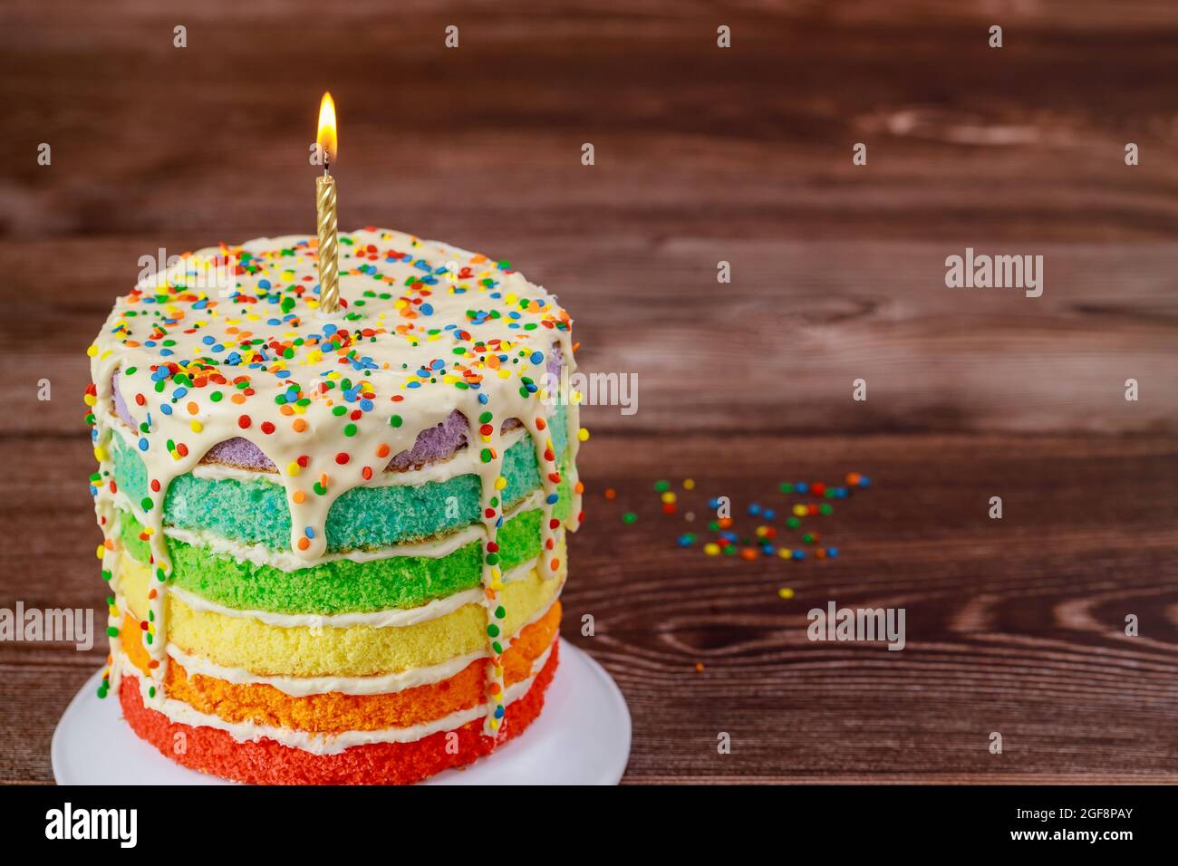 Birthday cake with burning candle and sprinkles Stock Photo - Alamy