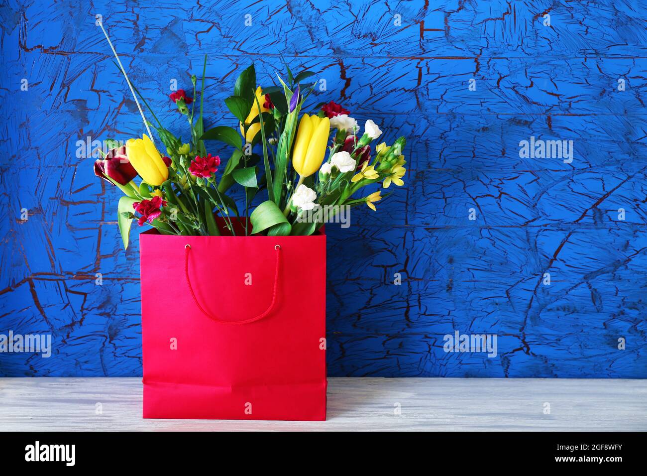 Bouquet of fresh flowers in a bag on blue background Stock Photo Alamy