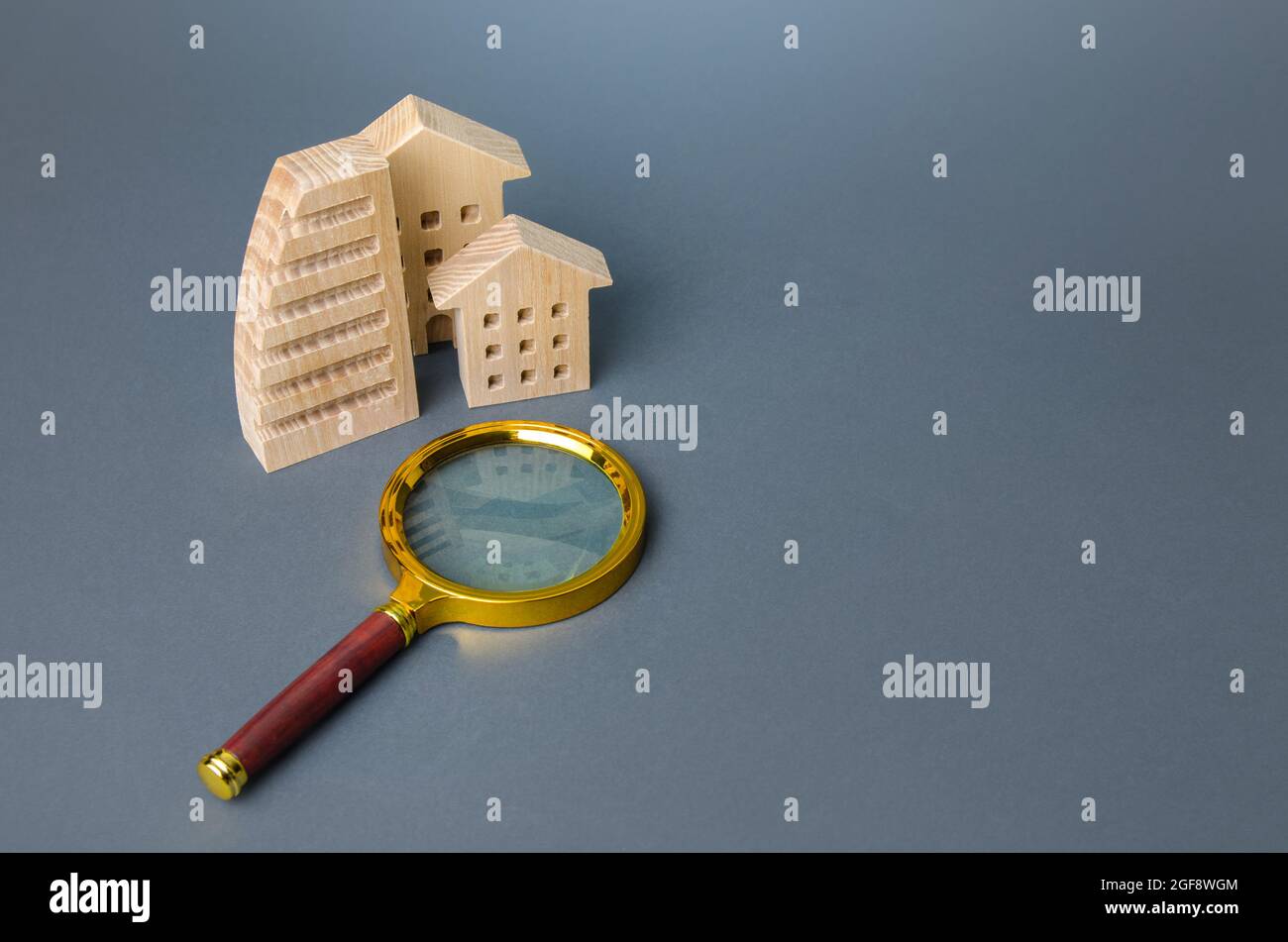 Figures of buildings and a magnifying glass. Apartment search. Buying or renting housing. Realtor service. Real estate market monitoring. Online booki Stock Photo