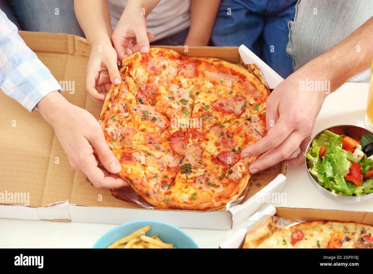 Happy family eating pizza on sofa all together Stock Photo - Alamy