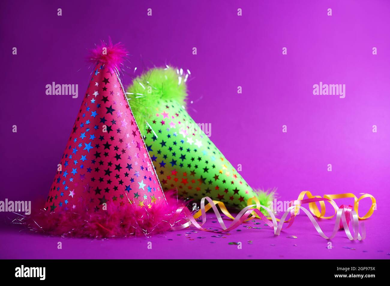 Funny party hats on purple background Stock Photo - Alamy