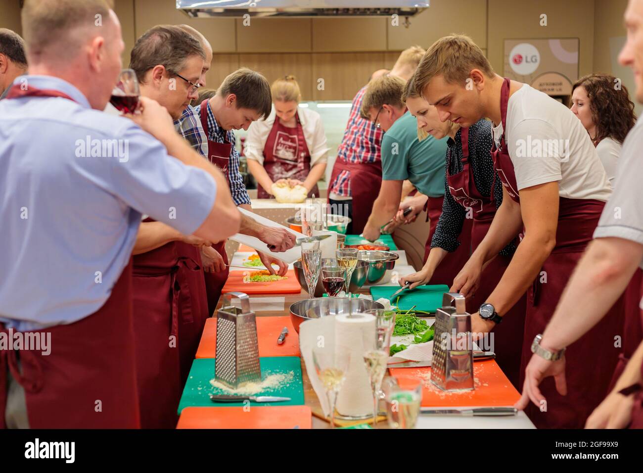 A group of colleagues celebrate a corporate lunch by cooking together. A community of people prepares lunch together in a large kitchen. Moscow, Russi Stock Photo