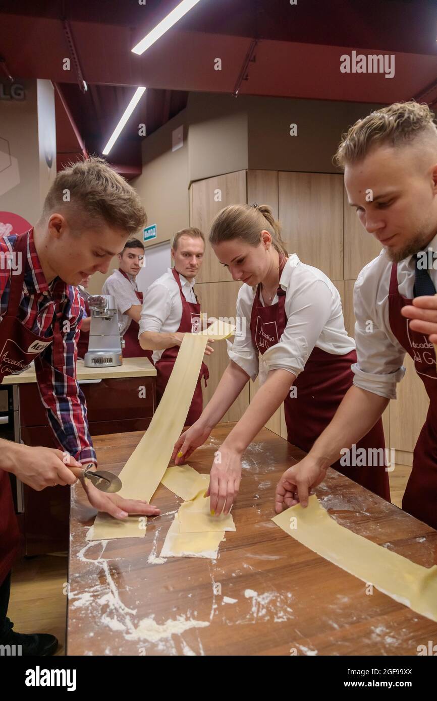 A group of colleagues celebrate a corporate lunch by cooking together. A community of people makes pasta dough together. Moscow, Russia August 19, 202 Stock Photo