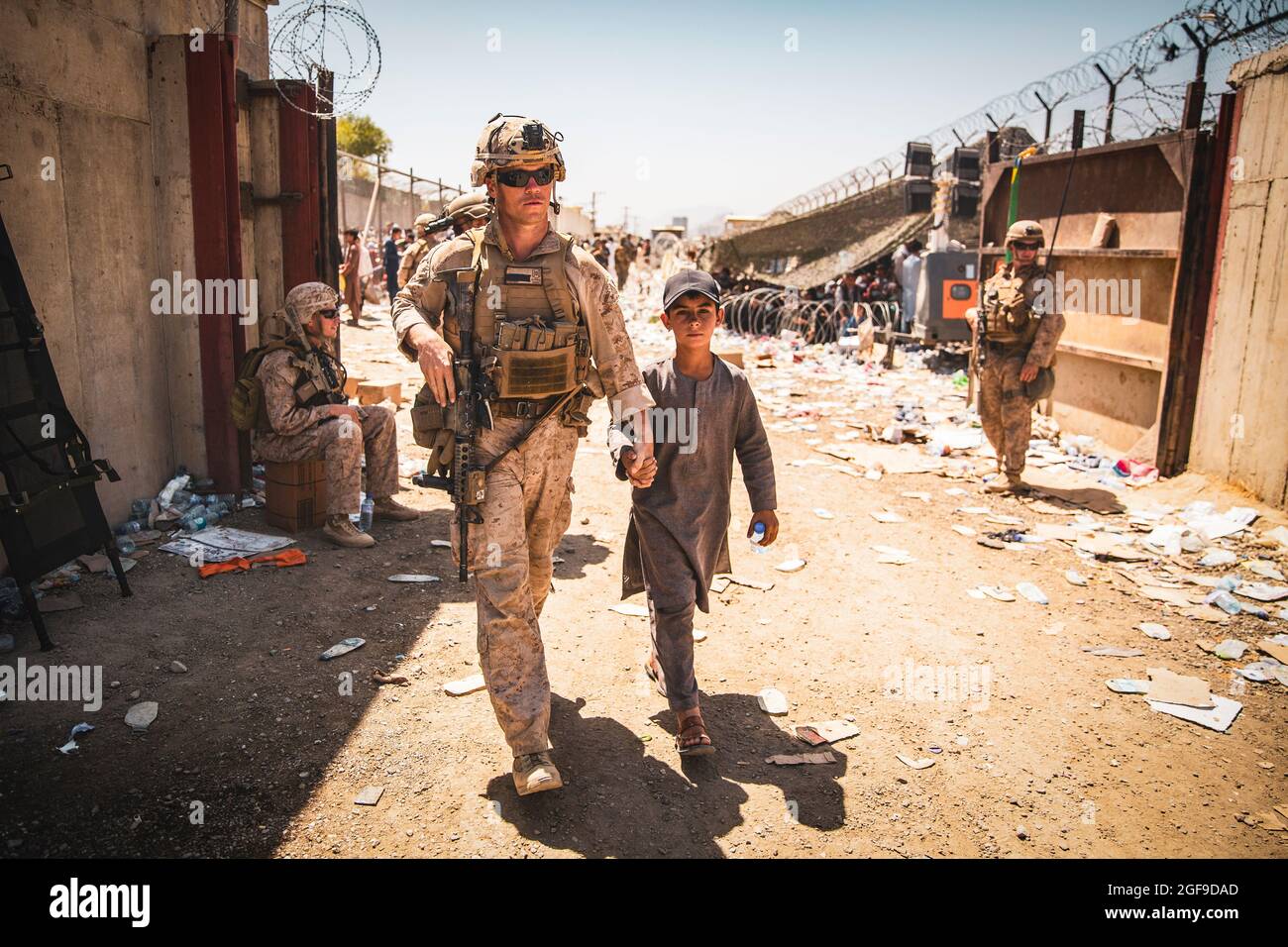 A U.S. Marine with the Special Purpose Marine Air-Ground Task Force-Crisis Response-Central Command (SPMAGTF-CR-CC) escorts a kid to his family during an evacuation at Hamid Karzai International Airport, Kabul, Afghanistan, Aug. 24. U.S. service members and coalition forces are assisting the Department of State with a non-combatant evacuation operation (NEO) in Afghanistan. (U.S. Marine Corps photo by Staff Sgt. Victor Mancilla) Stock Photo