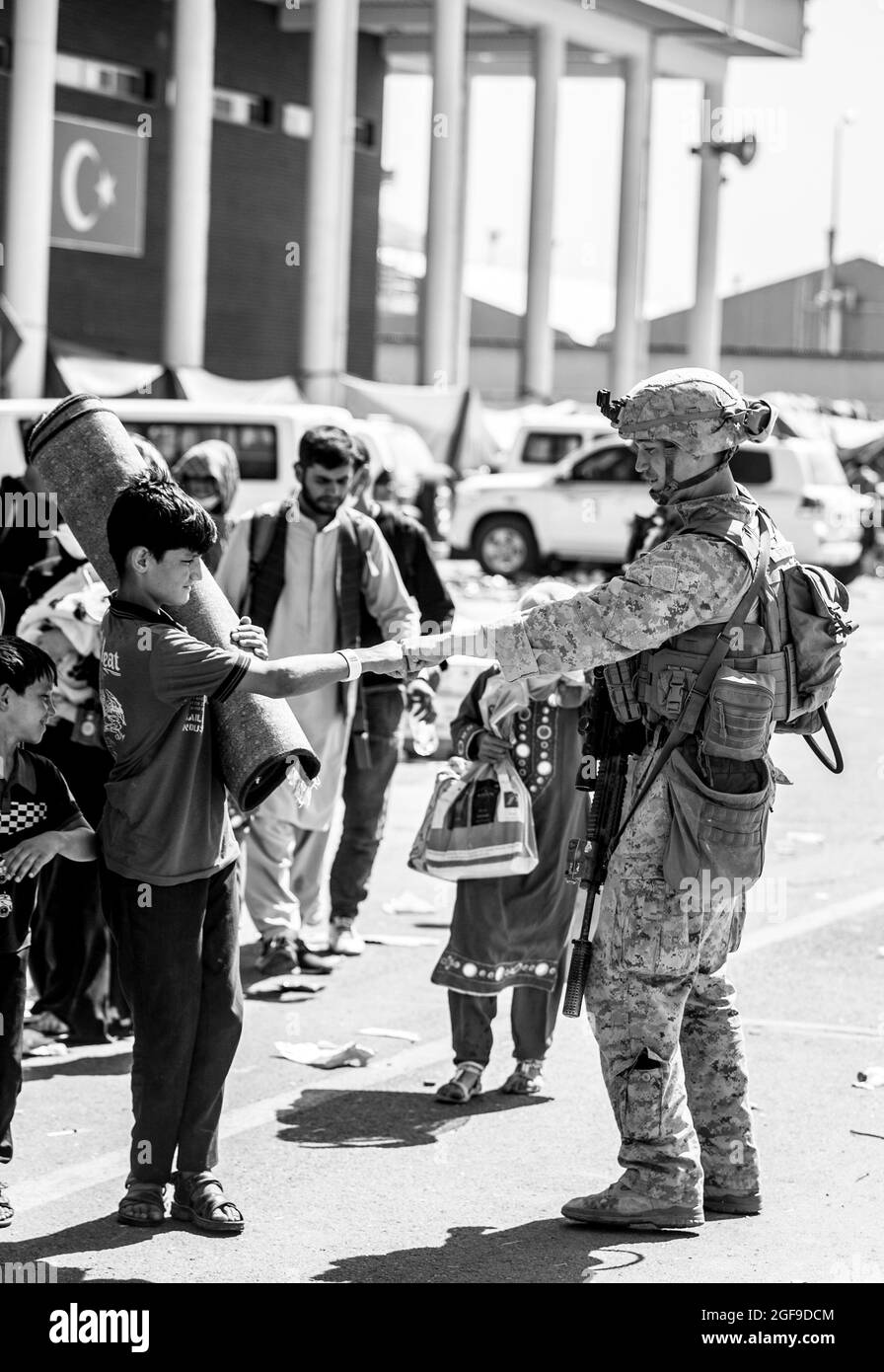 A Marine with Special Purpose Marine Air-Ground Task Force-Crisis Response-Central Command (SPMAGTF-CR-CC) shares a fist-bump with a child during an evacuation at Hamid Karzai International Airport, Kabul, Afghanistan, Aug. 24. U.S. service members are assisting the Department of State with an orderly drawdown of designated personnel in Afghanistan. (U.S. Marine Corps photo by Sgt. Samuel Ruiz). Stock Photo