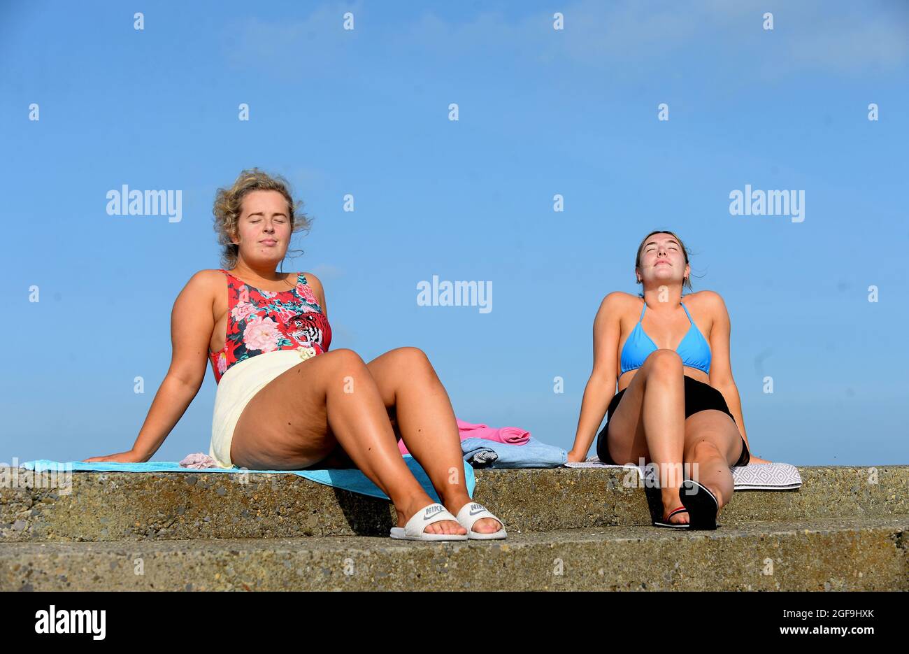 Tara Canny (left), from Athboy, Co. Meath, and Kate Eakins, from Ballina, Co. Mayo, enjoying the sun on Bull Wall, Clontarf, Dublin, Ireland. Picture date: Tuesday August 24, 2021. Stock Photo