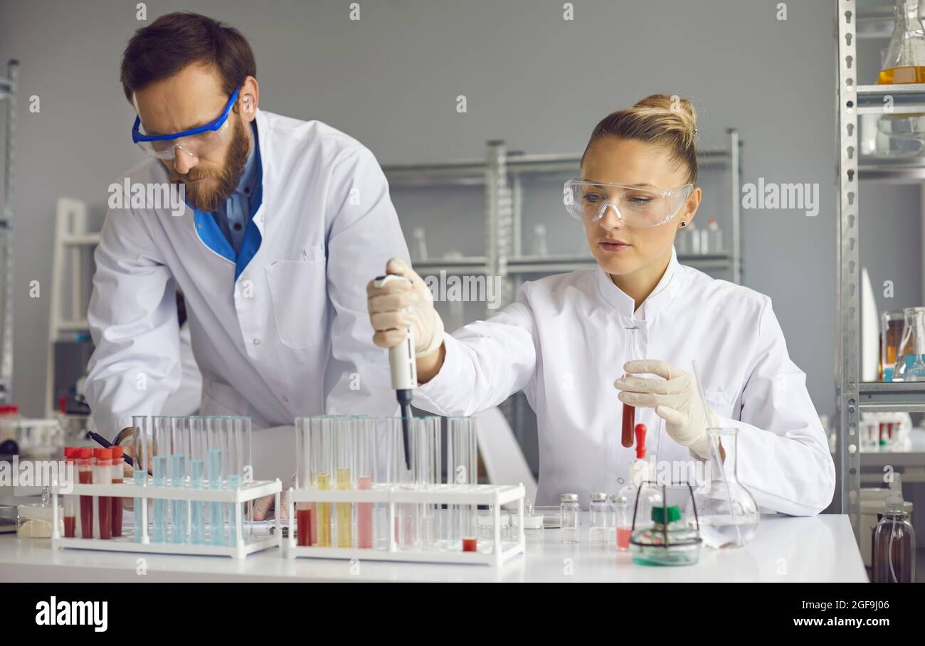 Team of focused scientists working together on sample analyzes while working in a lab. Stock Photo