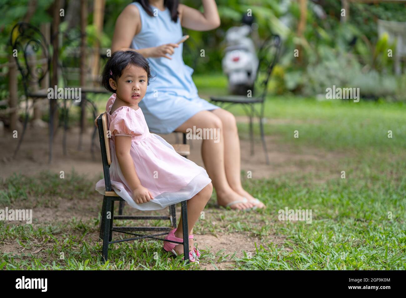 Selective focus of a cute little Asian girl sitting on a chair in a ...