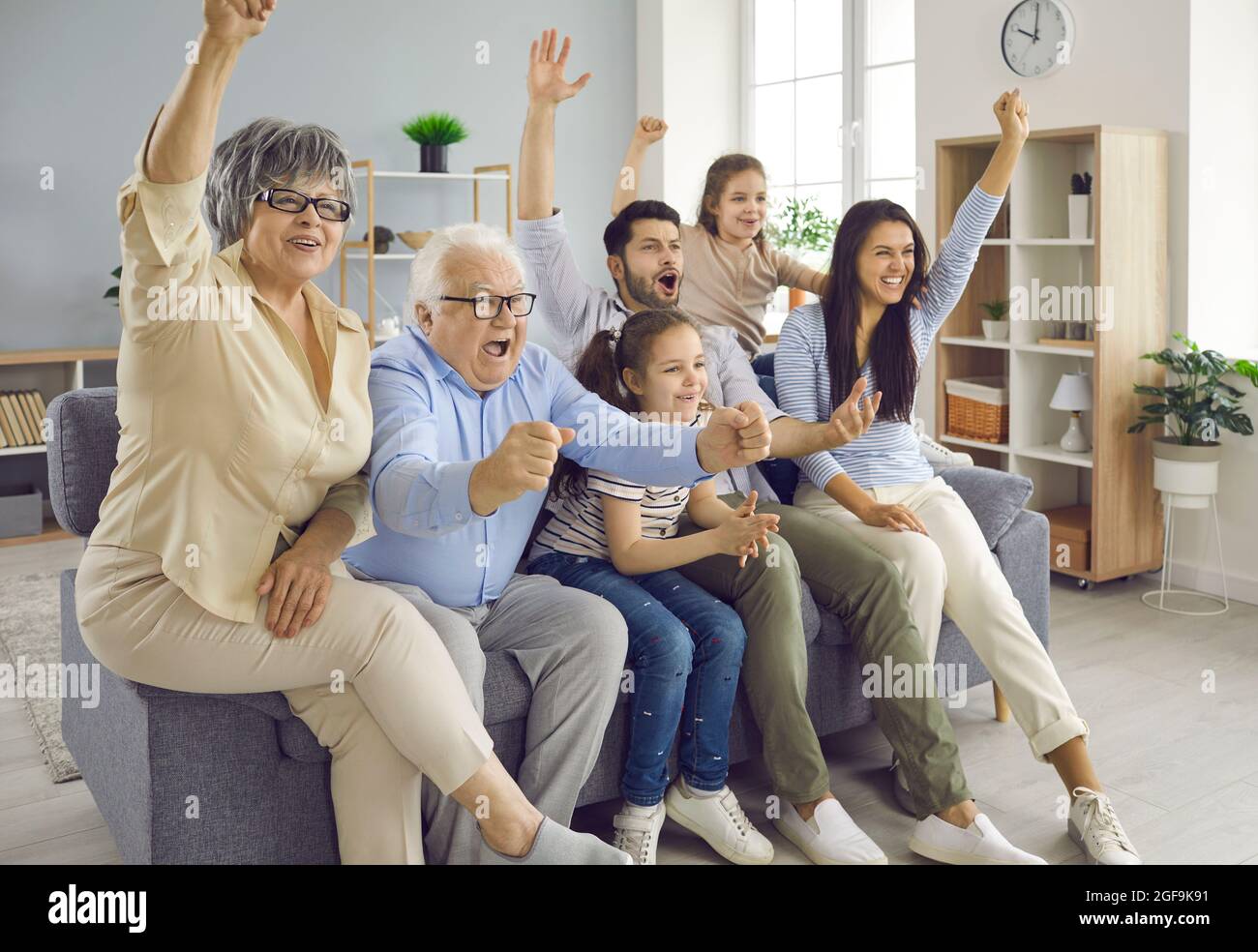 Excited happy big family of different generations watching football match on sofa at home. Stock Photo