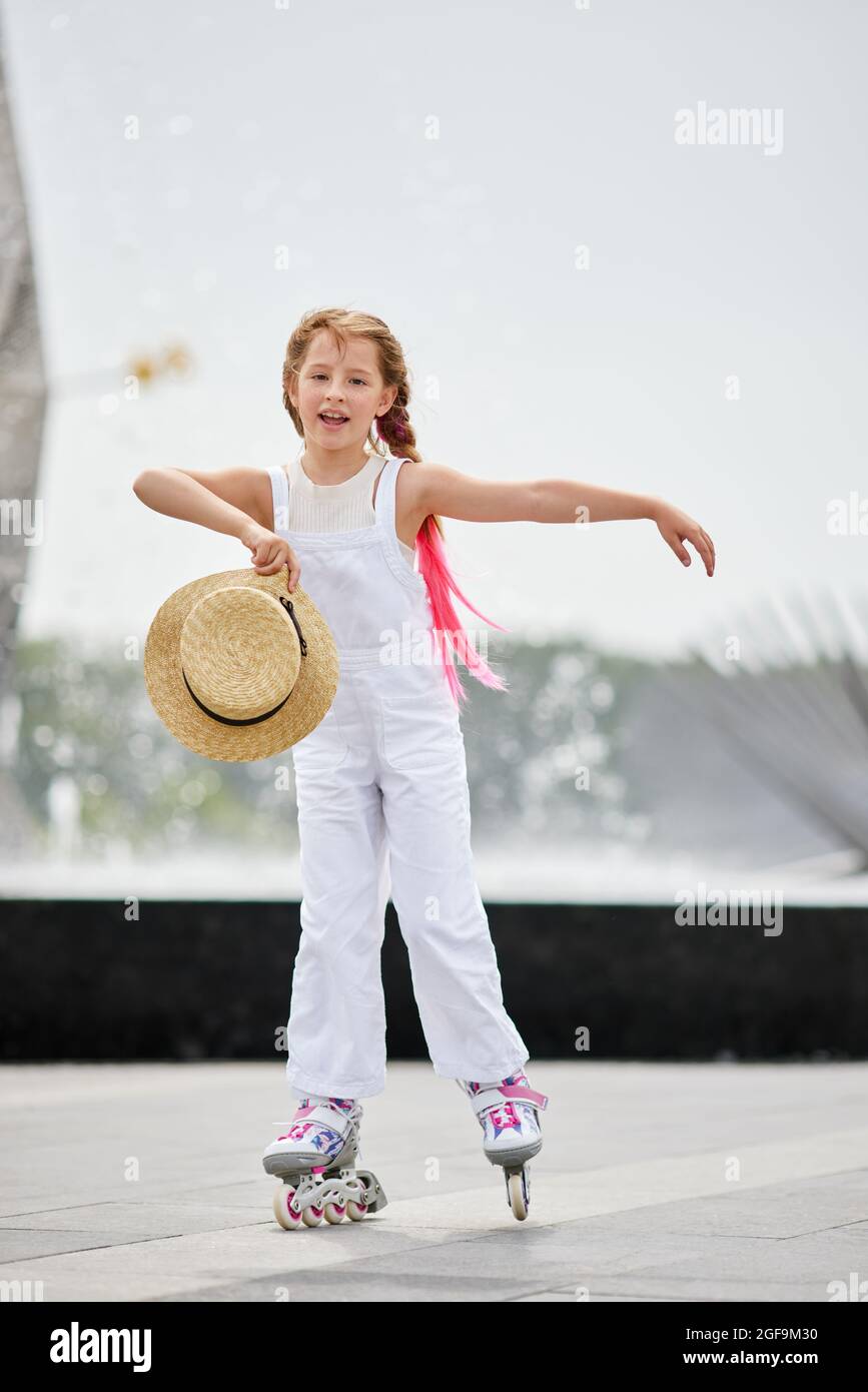 Close up beautiful slim legs of young girl in short shorts wearing roller  skating in a sunny day in summer in the park. Knee protectors Stock Photo