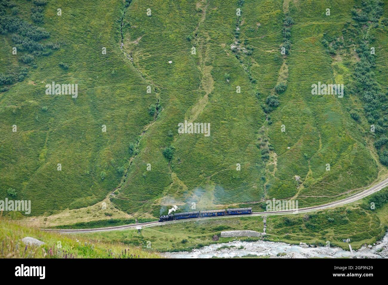 Furka steam train through the mountain landscapes of the Central Alps on the historic Glacier Express route. Furkapass, Switzerland - August 2021 Stock Photo