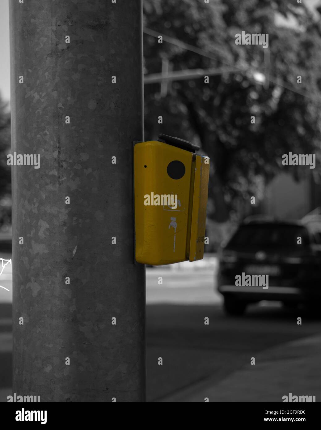 Yellow traffic light switch for pedestrian crossing on a black and