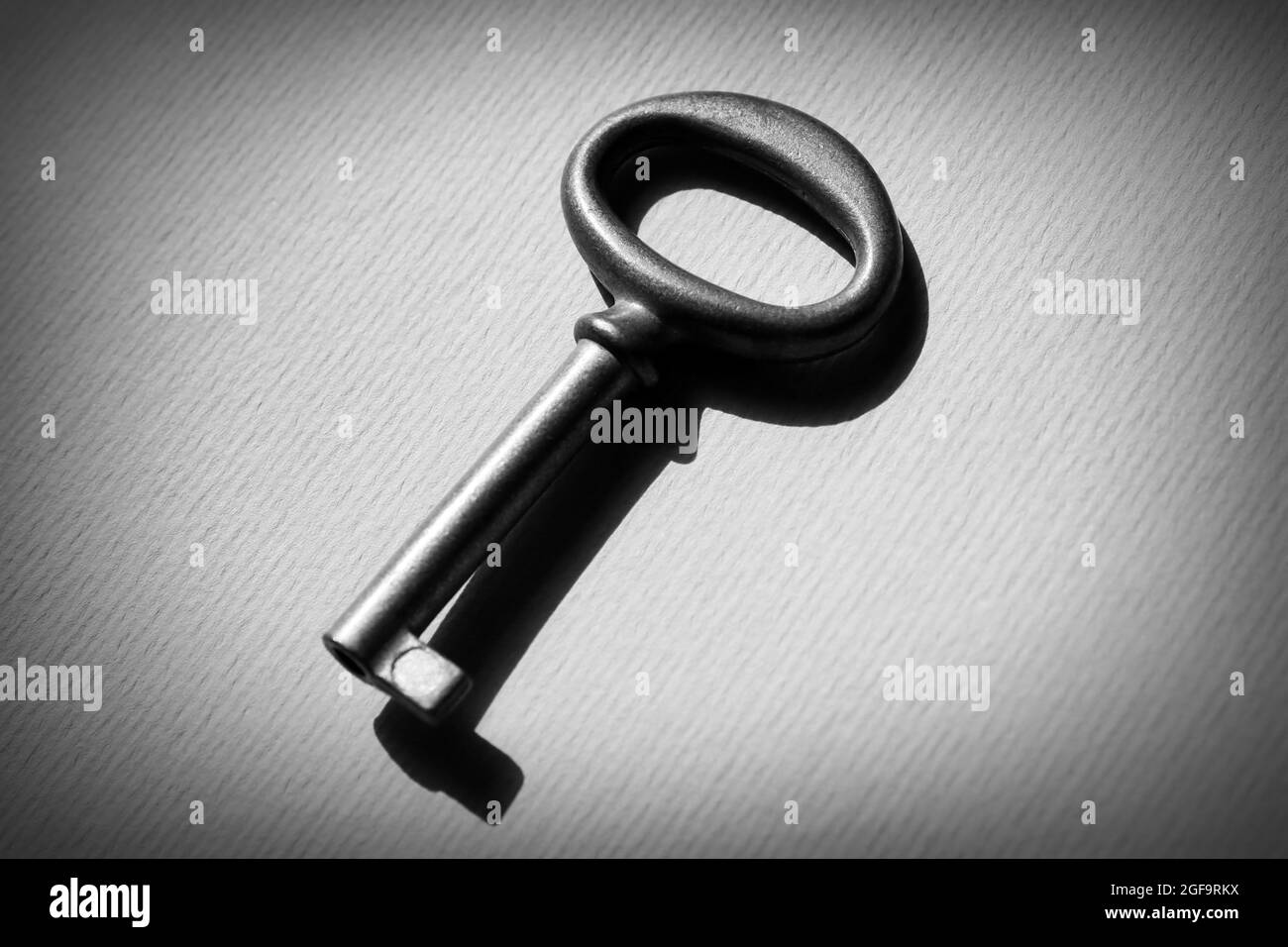 Vintage key on light paper background Stock Photo - Alamy