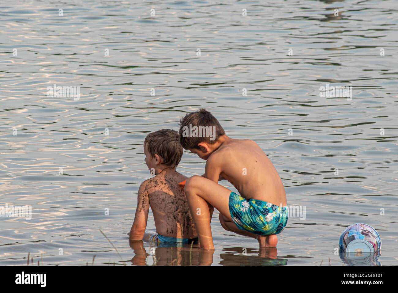 Little boys playing with mud on the lake Stock Photo