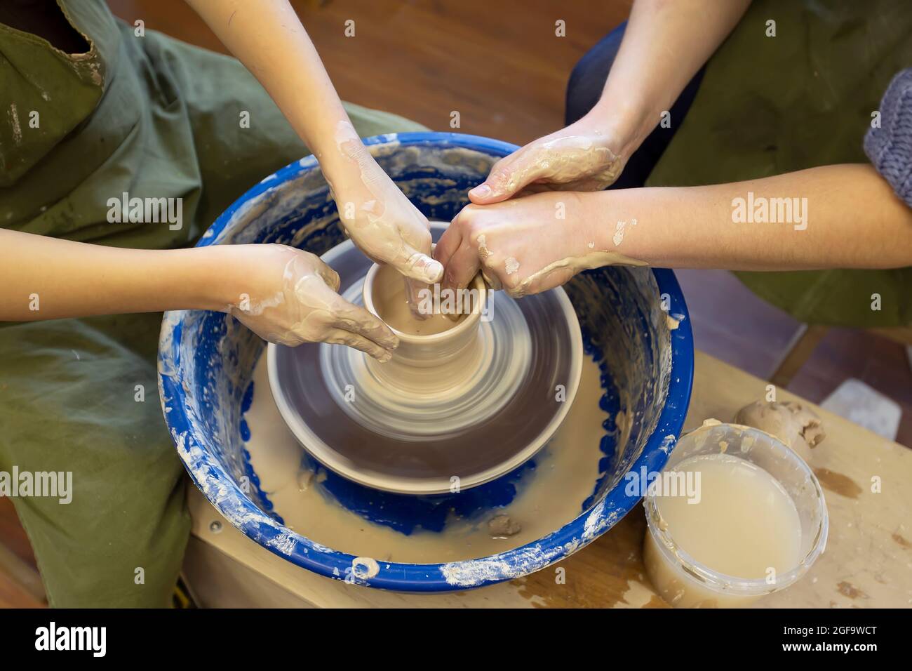 Closeup of a potter's hands and a child's hand with an item on a