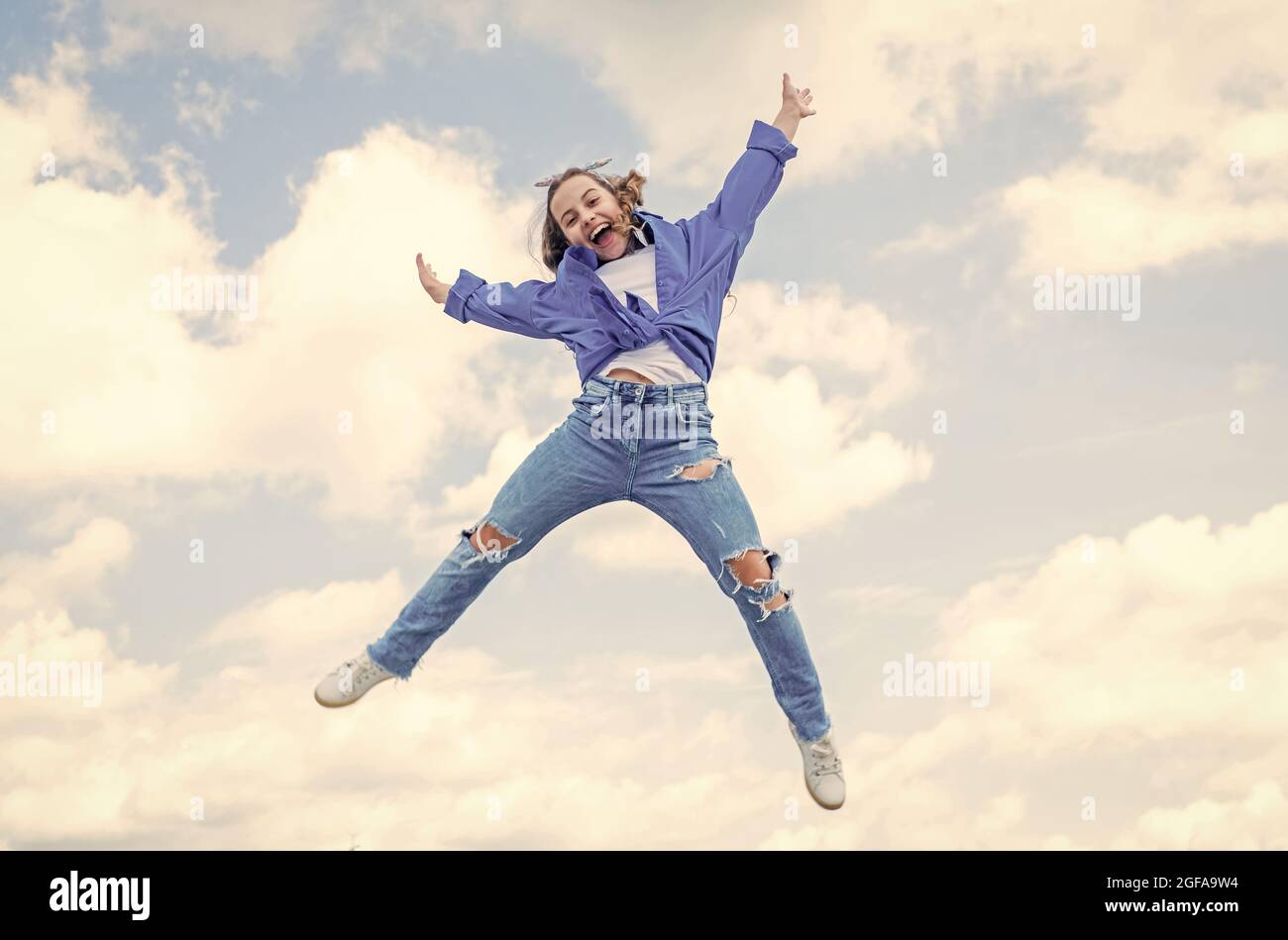 full of energy. childhood happiness. teen girl jumping high in the sky ...