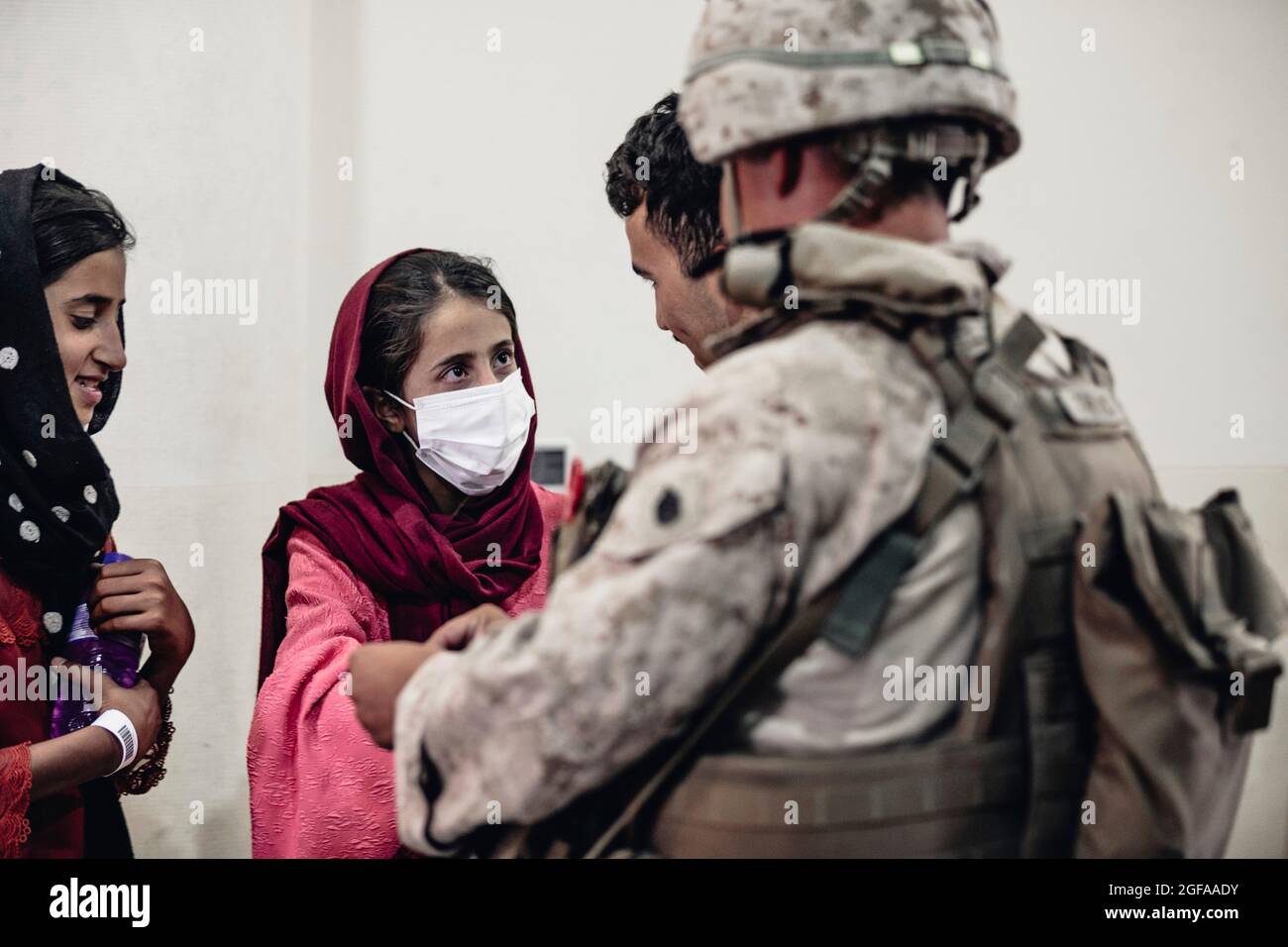 Kabul, Afghanistan. 24th Aug, 2021. A U.S. Marine assigned to Special Purpose Marine Air-Ground Task Force - Crisis Response team assists Afghan refugees at Hamid Karzai International Airport during Operation Allies Refuge August 24, 2021 in Kabul, Afghanistan. Credit: Planetpix/Alamy Live News Stock Photo
