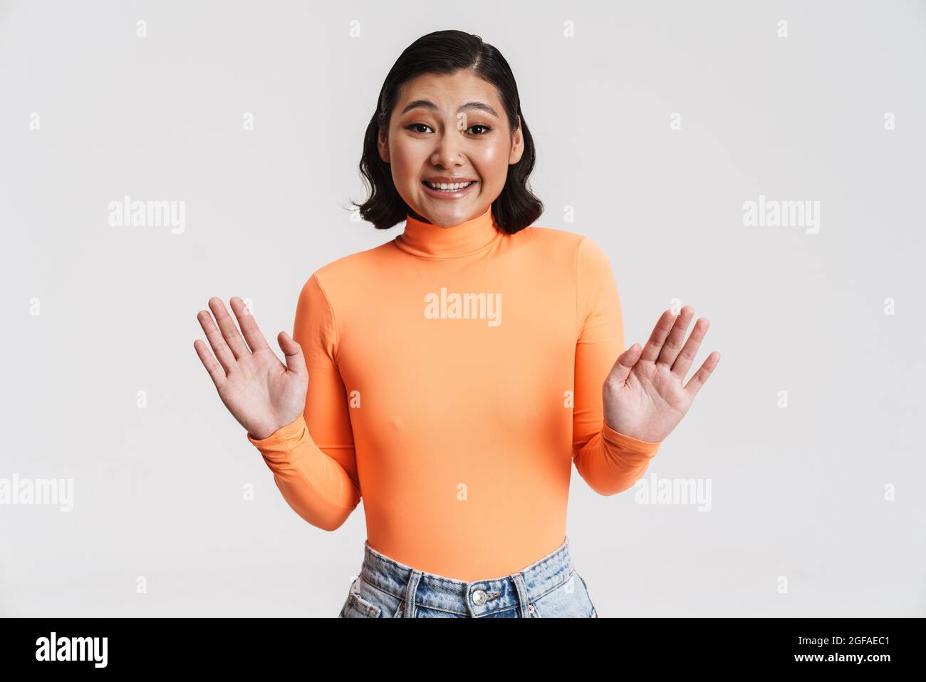 Portrait of a confused casual brunette young asian woman standing over blue background hands outstretched Stock Photo