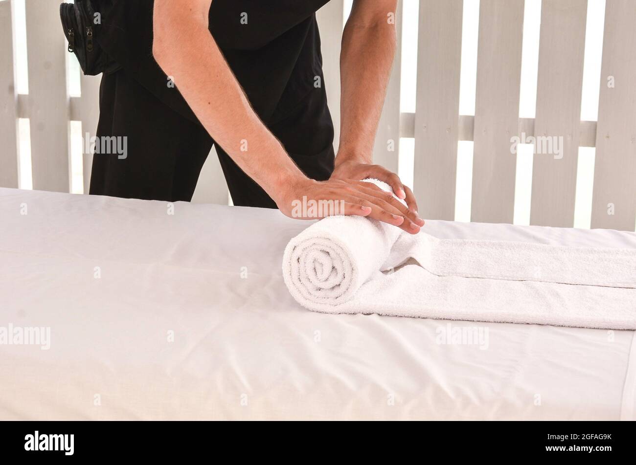 Male's hand folding a towel on a massage table Stock Photo