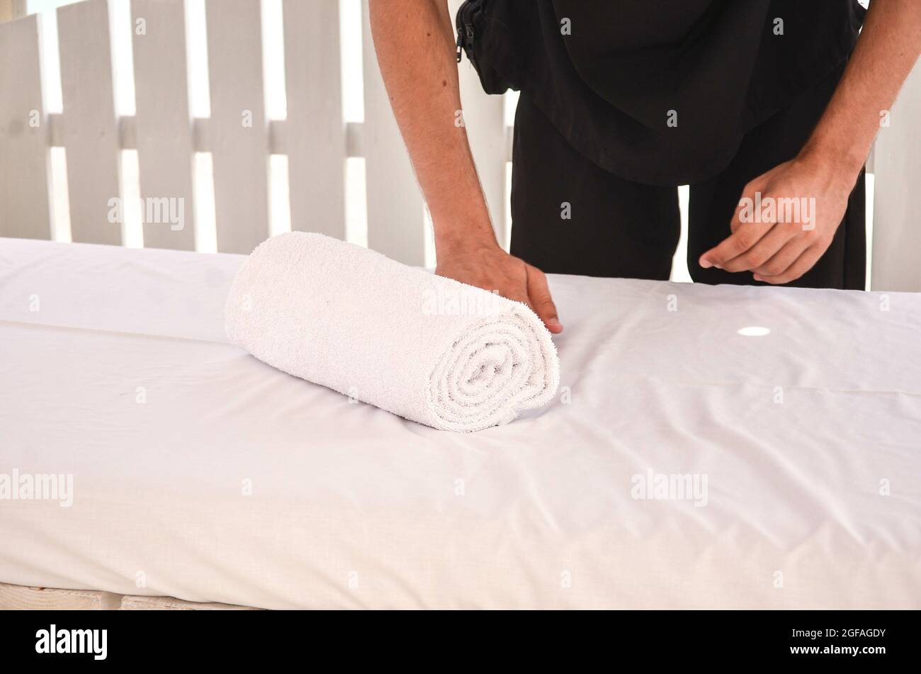 Male's hand folding a towel on a massage table Stock Photo
