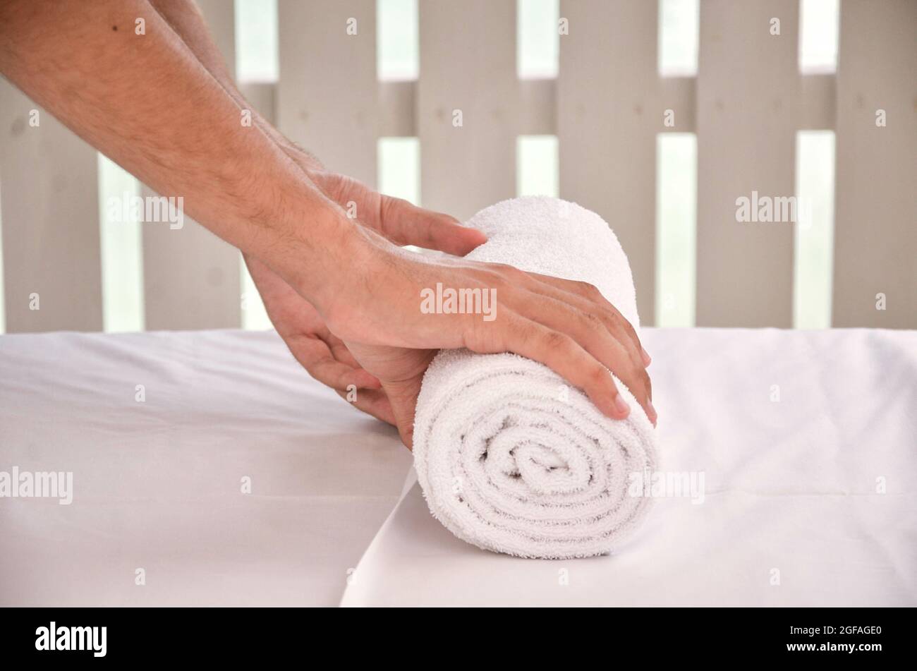 Male's hand folding a towel on a massage table Stock Photo