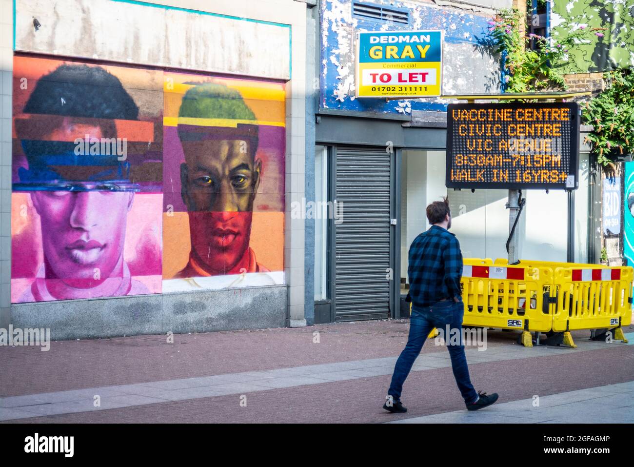 COVID vaccine centre sign, closed, boarded up shops in High Street