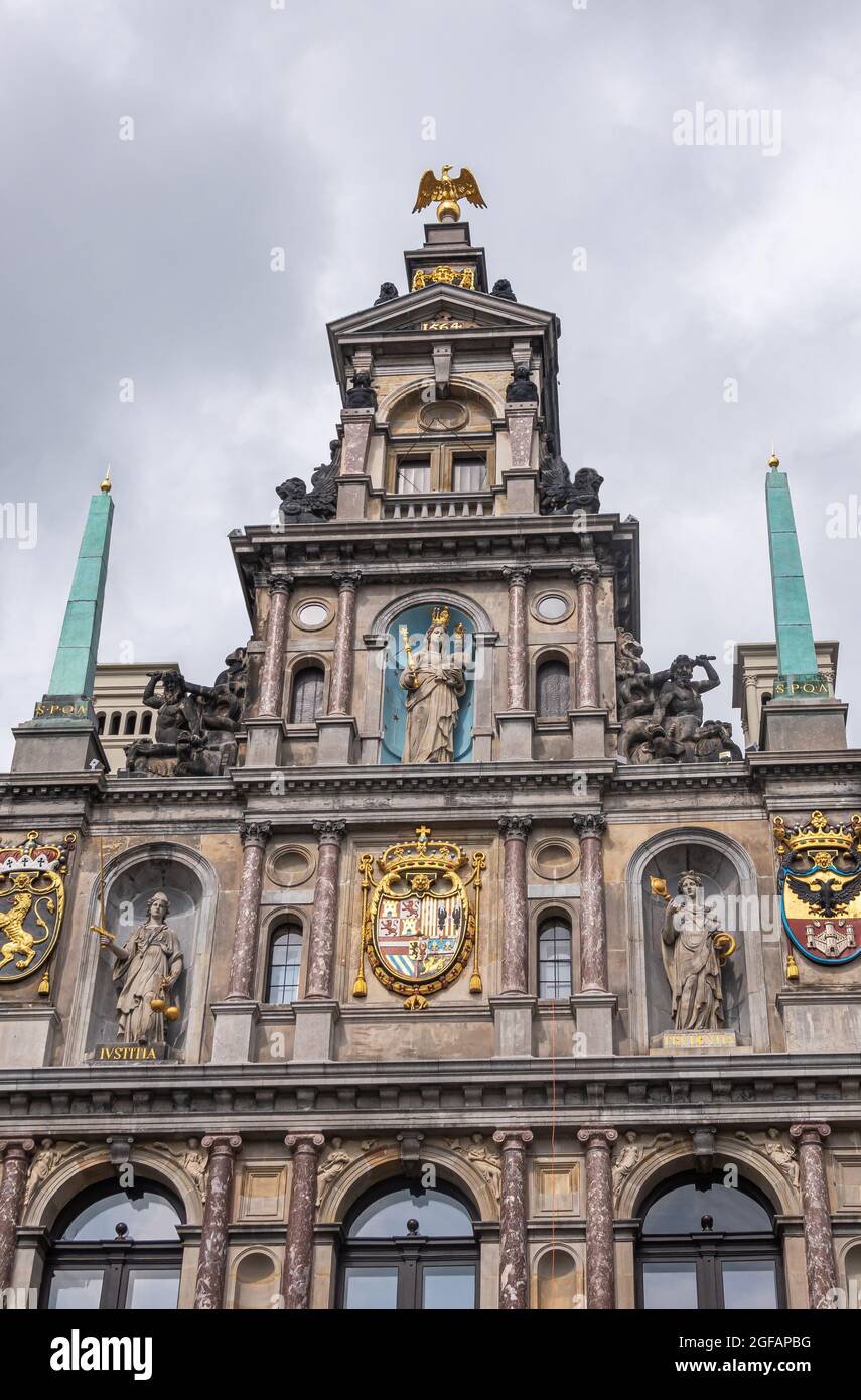 Antwerpen, Belgium - August 1, 2021: Closeup of historic and iconic City hall gable top against gray cloudscape. Golden ornaments and staties in niche Stock Photo