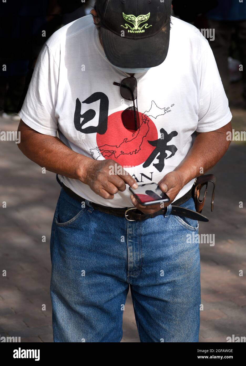 A man wearing a 'Japan' T-shirt uses his smartphone in Santa Fe, New Mexico. Stock Photo