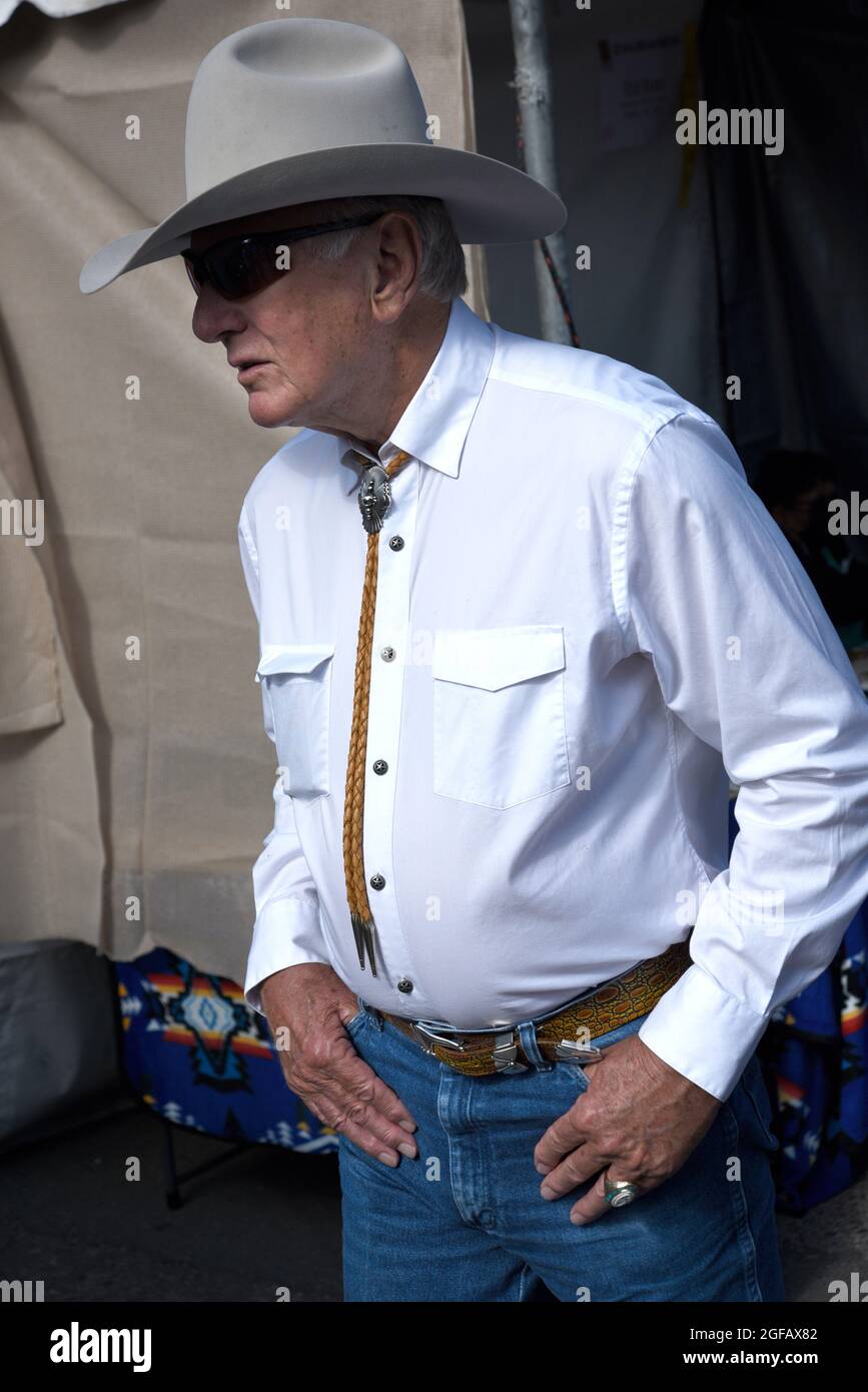 A well-dressed senior man wearing American western attire visits an outdoor art show in Santa Fe, New Mexico. Stock Photo