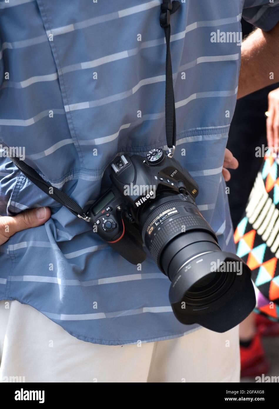 A man carries his Nikon camera on a strap behind his back as he photographs an outdoor art show in Santa Fe, New Mexico. Stock Photo