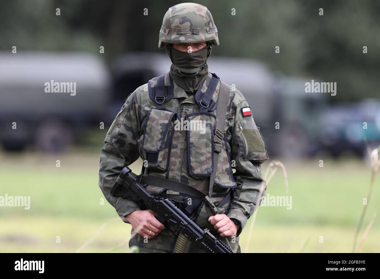 A soldier is seen guarding the area surrounding the border with Belarus where 32 Afghan refugees have been stuck in Usnarz Gorny, Poland on August 24, 2021. For 16 days in a row 32 Afghan refugees have been stuck at the Polsh-Belarusian border without food or shelter. Polish authorities deny the migrants have ever reached Polish soil contraty to reports from local individuals who have stated the group has been pushed back by border guards. In August of this year nearly 3000 refugees have been reported attempting to cross the border compred to less than 100 in all of 2020. The surge in border c Stock Photo