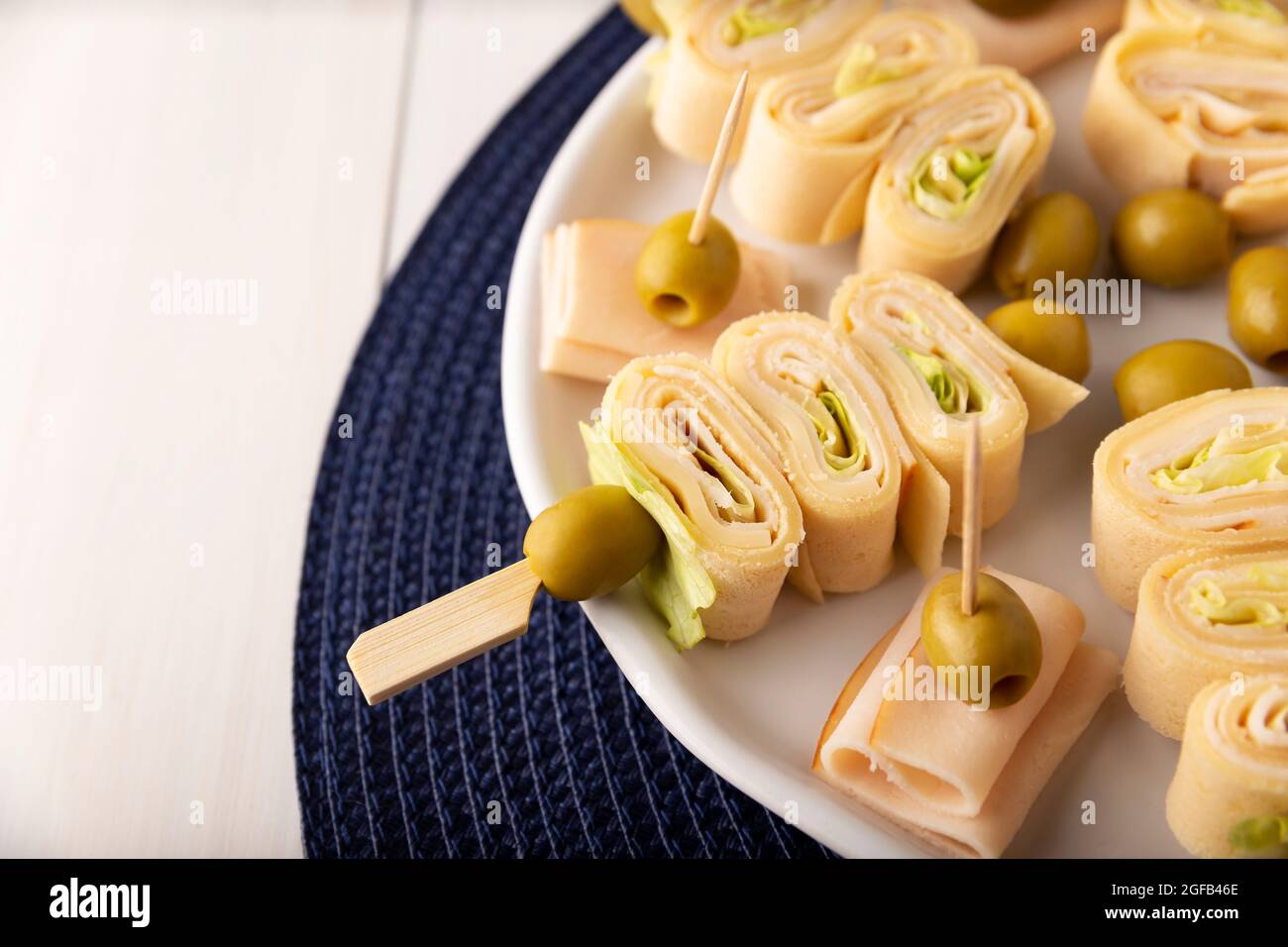 Party Snacks. Crepe Rolls with ham and cheese on a stick decorated with olive Stock Photo