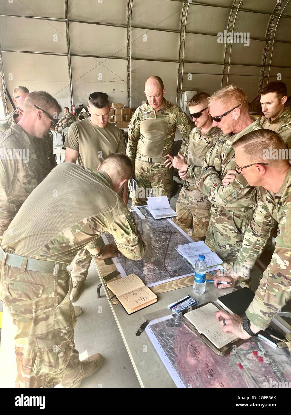 Army Maj. Joseph Genin, Task Force operations officer, briefs Battalion Commander Lt. Col. Jacob Helgestad, company commanders, and task force staff on current operations at Hamid Karzai International Airport on August 21, 2021. With its strategic assignment at Camp Buehring, Task Force 1-194 was positioned to respond to the Noncombatant Evacuation Operation announced by the Department of State and supported by the Department of Defense.  Approximately 1,100 Soldiers from Task Force 1-194 deployed to the Middle East in early 2021 for a nine-month mission in support of Operation Spartan Shield. Stock Photo