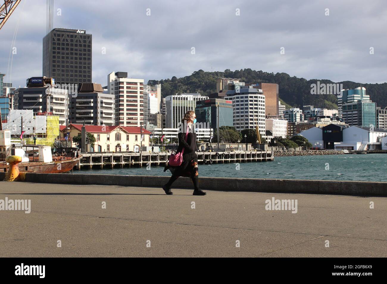 Wellington, New Zealand, 25 August 2021. A woman in a face mask walks along the waterfront in Wellington, New Zealand during a strict Level 4 lockdown due to a Covid-9 delta variant outbreak. Credit: Lynn Grieveson/Alamy Live News Stock Photo