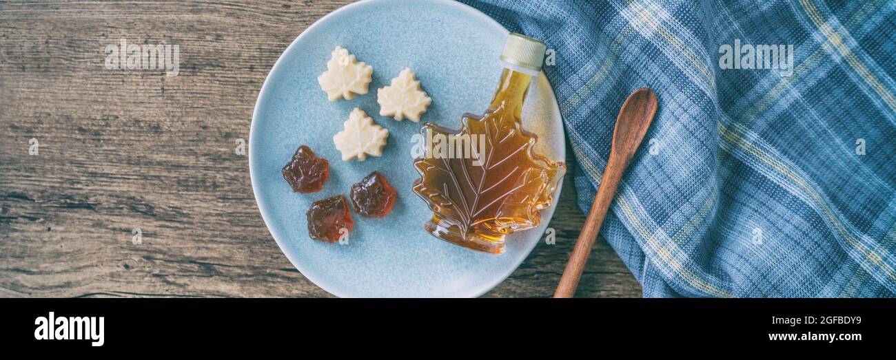 Maple syrup bottle and pure soft sugar candy and taffy top view on kitchen table panoramic banner. Cooking ngredient for desssert recipe, traditonal Stock Photo