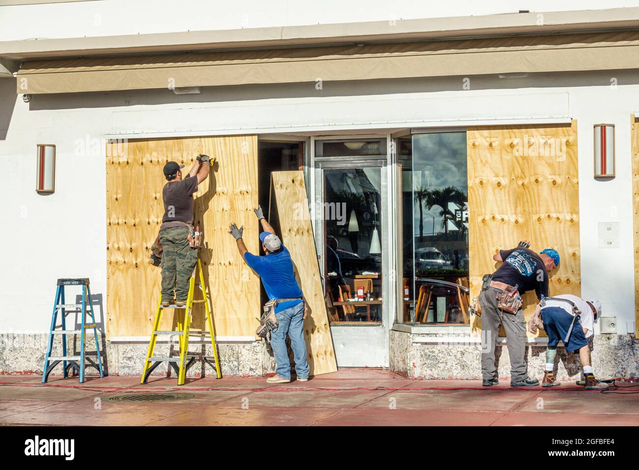 Miami Beach Florida,TGI Friday's restaurant business,Hurricane Irma approaching,plywood barrier boarding windows workers preparing man men ladder, Stock Photo