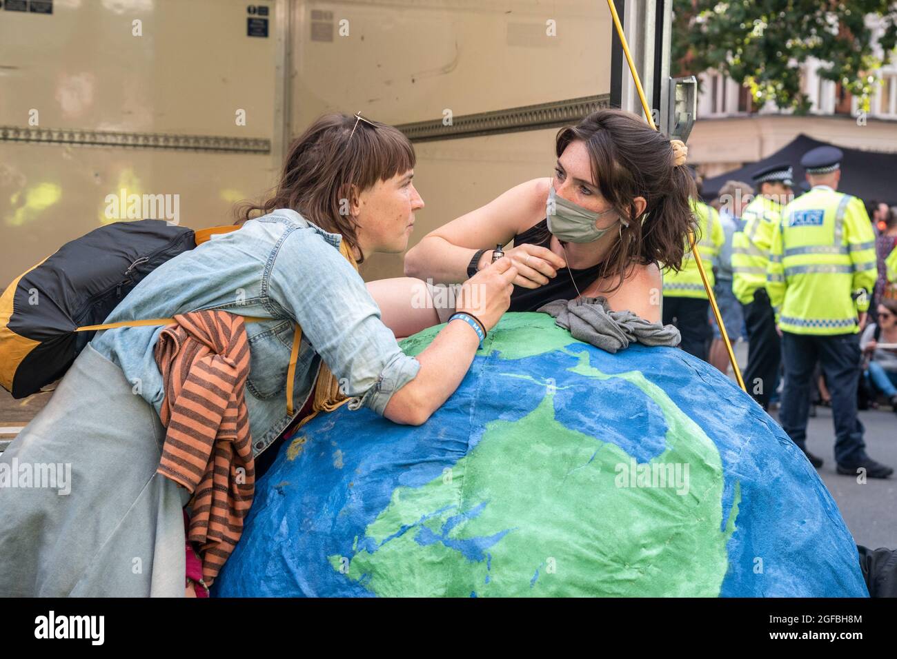 London, UK. 24th Aug, 2021. Protesters chained to a globe at Cambridge Circus, during the demonstration.‘The Impossible Rebellion' protest against climate change, global warming, which plans to target the root cause of the climate and ecological crisis and to demand the government divest from fossil fuel companies by Extinction Rebellion. Credit: SOPA Images Limited/Alamy Live News Stock Photo