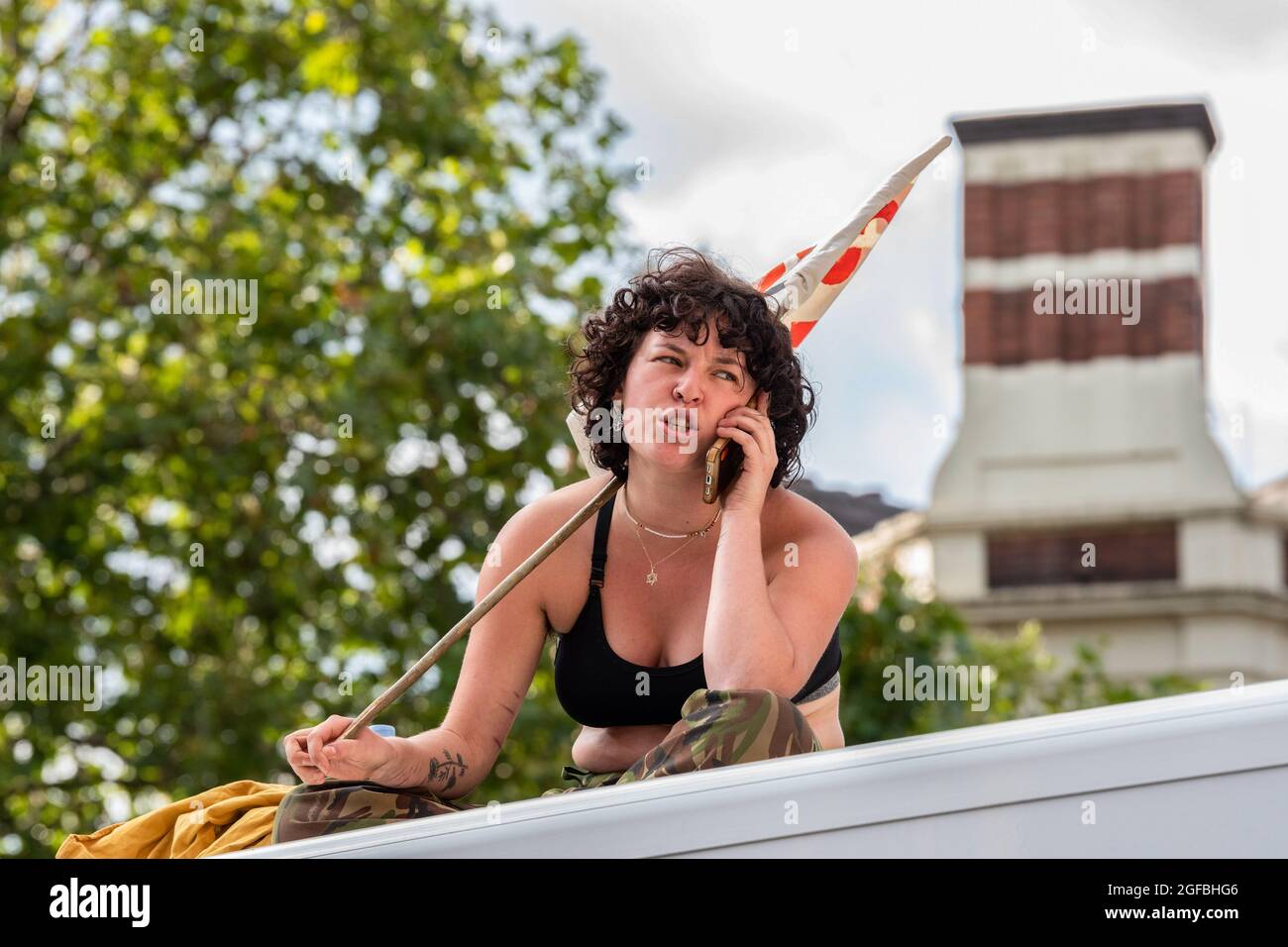 London, UK. 24th Aug, 2021. A protester on the roof of a van chats on her phone at Cambridge Circus, during the demonstration.‘The Impossible Rebellion' protest against climate change, global warming, which plans to target the root cause of the climate and ecological crisis and to demand the government divest from fossil fuel companies by Extinction Rebellion. (Photo by Dave Rushen/SOPA Images/Sipa USA) Credit: Sipa USA/Alamy Live News Stock Photo
