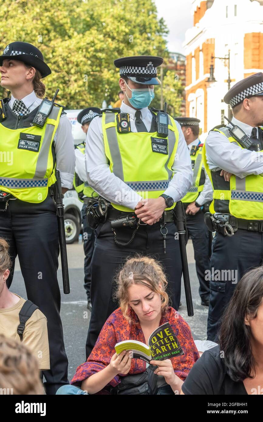 London, UK. 24th Aug, 2021. Police standing next to protesters sitting in the road at Cambridge Circus during the demonstration.‘The Impossible Rebellion' protest against climate change, global warming, which plans to target the root cause of the climate and ecological crisis and to demand the government divest from fossil fuel companies by Extinction Rebellion. (Photo by Dave Rushen/SOPA Images/Sipa USA) Credit: Sipa USA/Alamy Live News Stock Photo