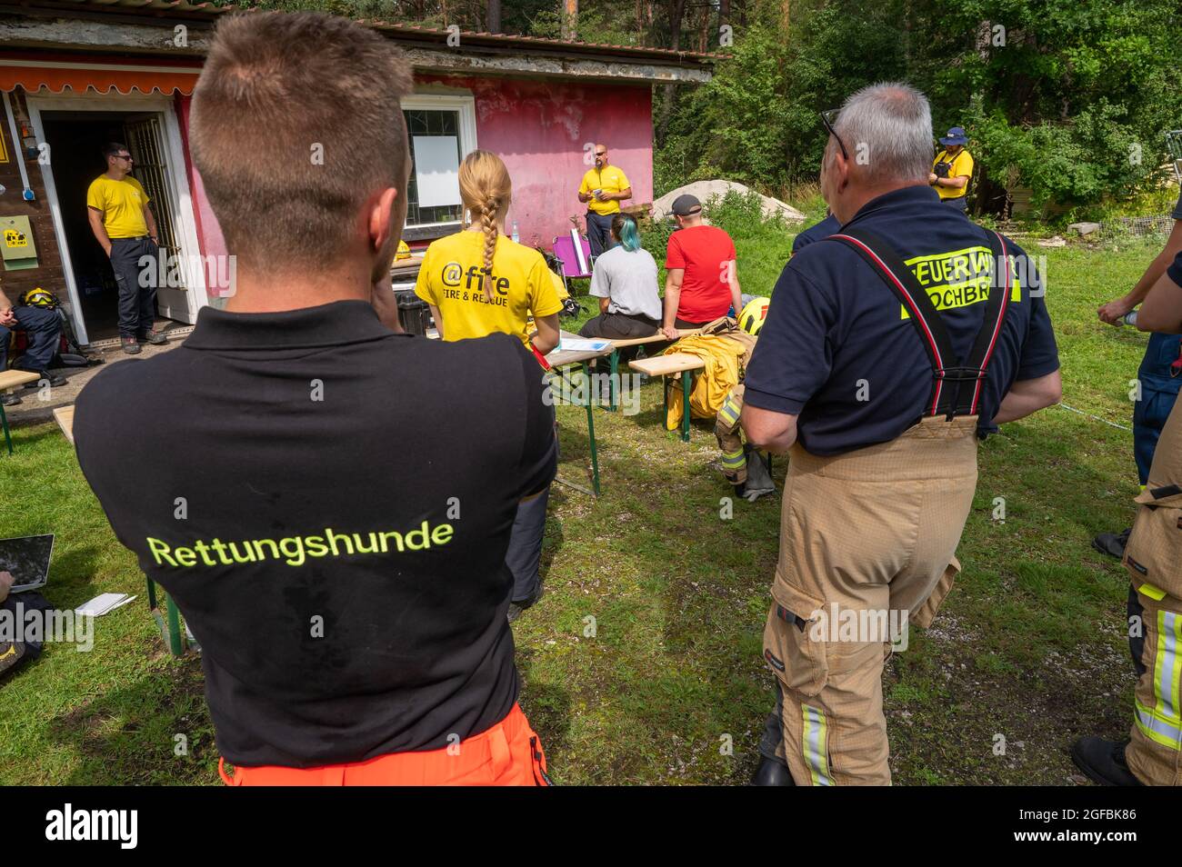 Garching, Germany. 21st Aug, 2021. Irakli West (back M) of '@fire' gives explanations during an exercise of different disaster control organisations on a developed rubble site north of the Bavarian capital. Credit: Peter Kneffel/dpa/Alamy Live News Stock Photo