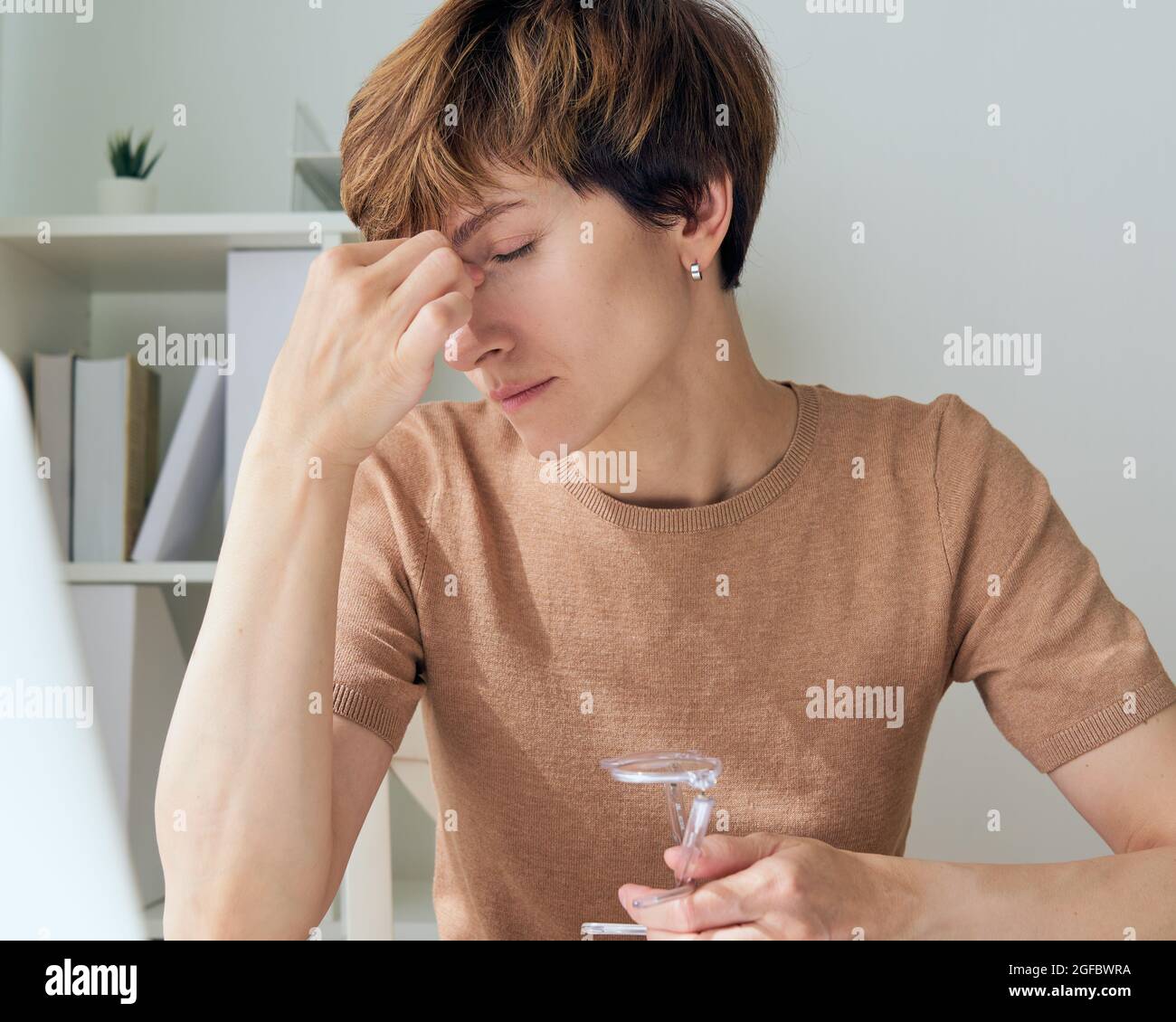 Woman touching forehead and feeling frustrated and stressed due to remote work from home Stock Photo