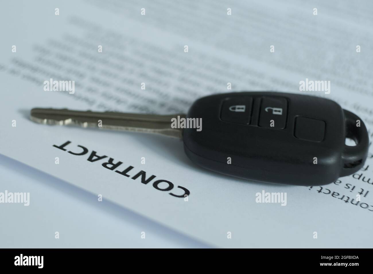 There is a contract and car keys on the table, the emphasis is on the name of the document and the keys.  Blurred image. Stock Photo