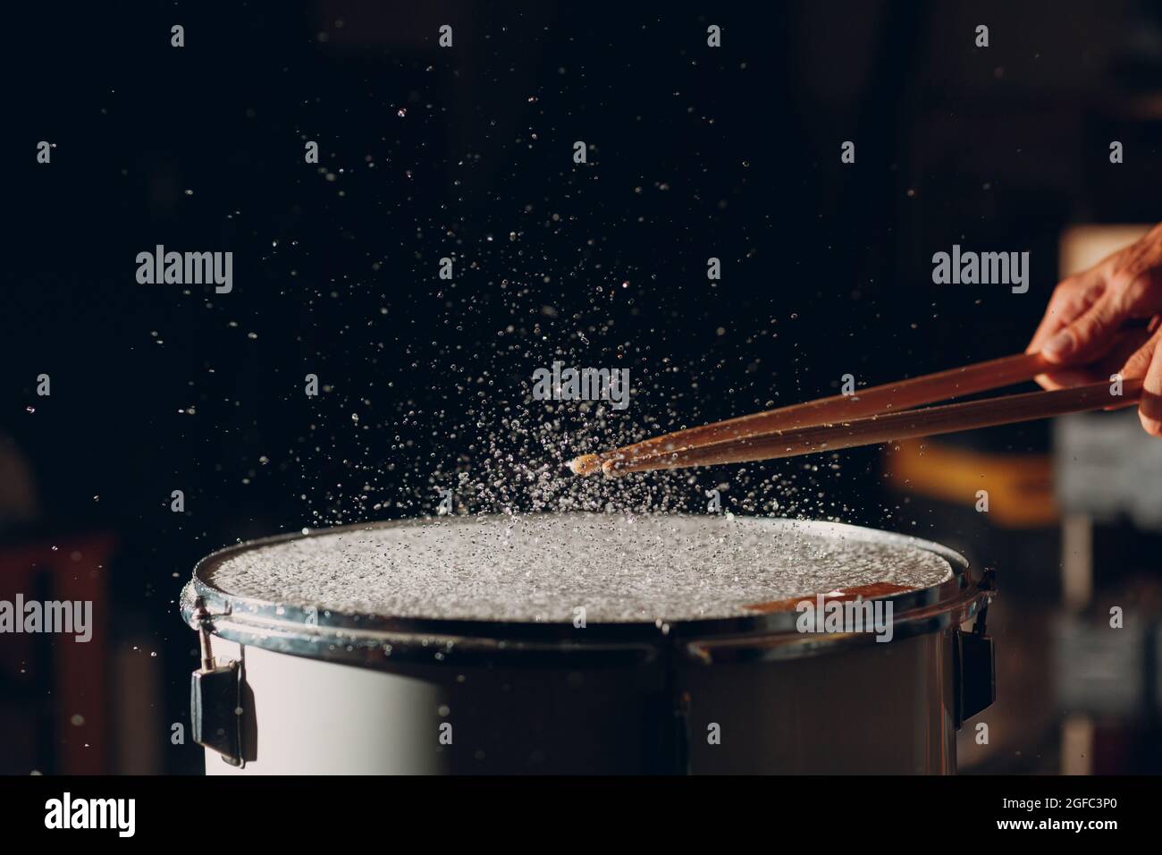 Close up drum sticks drumming hit beat rhythm on drum surface with splash water drops Stock Photo