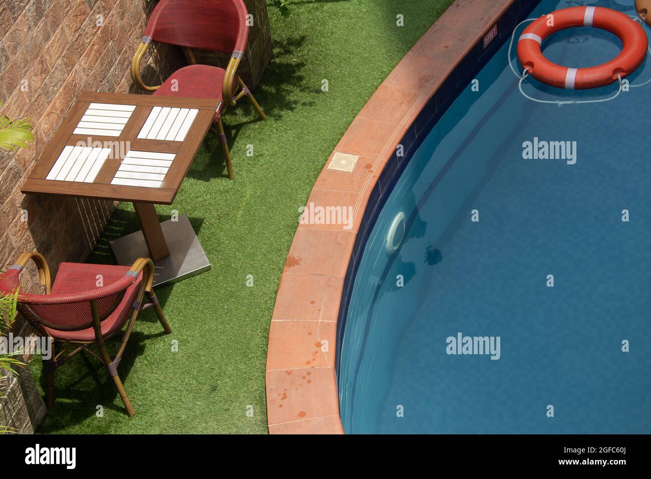 Small swimming pool in private luxury residence villa, with tables and chairs around, decorative plants and floating rings Stock Photo