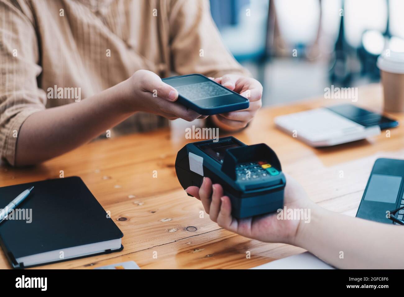 A woan using her mobile to made a payment wireless with EDC machine or ...