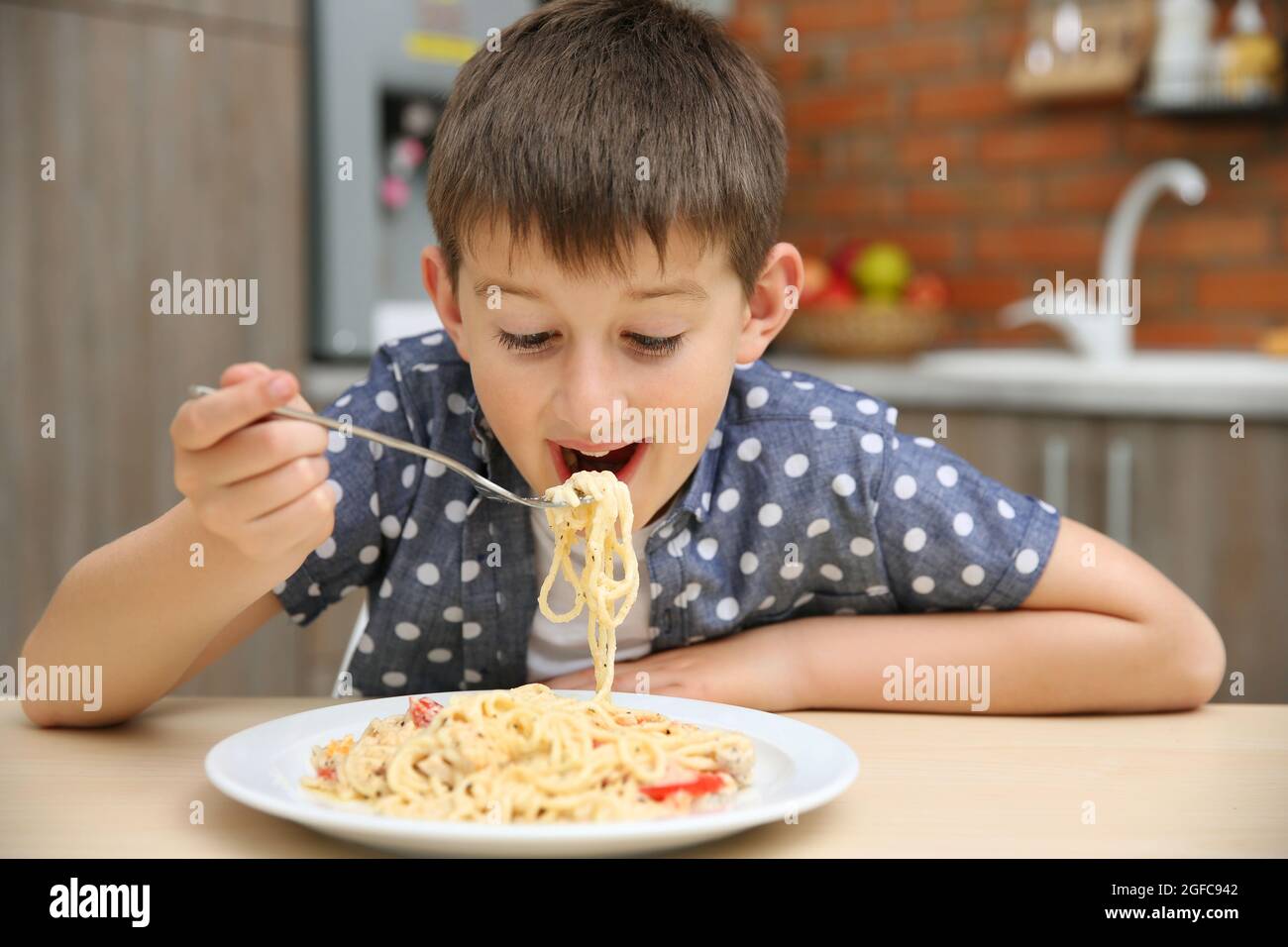 Cute boy eating spaghetti on kitchen Stock Photo - Alamy