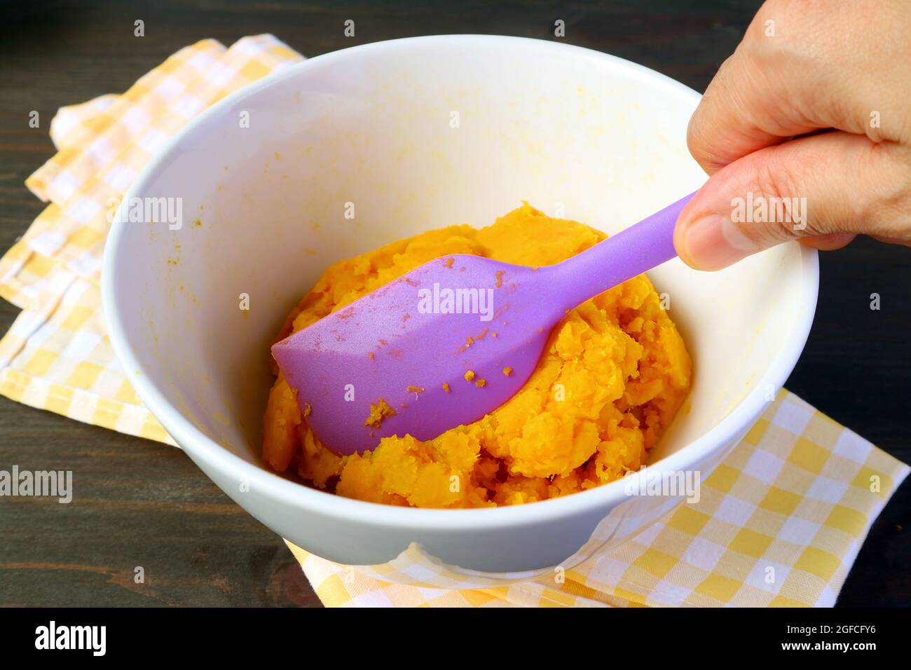 Man's Hand Holding Spatula Making Homemade Pumpkin Puree in a Mixing Bow Stock Photo