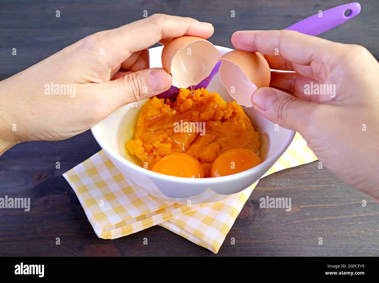 Hand Breaking an Raw Egg on Pumpkin Puree Bow for Pumpkin Pie Filling Stock Photo