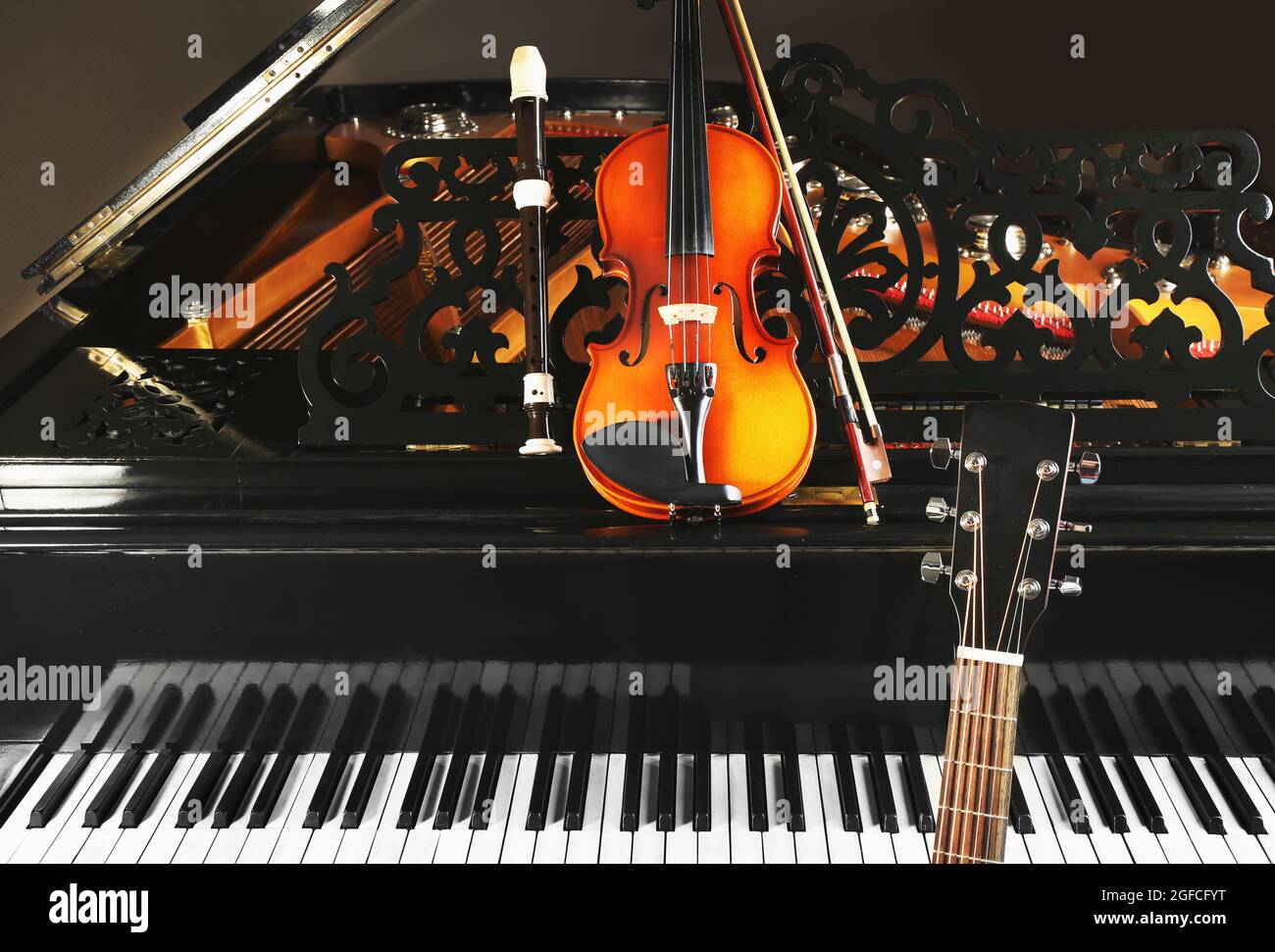 Flute, violin and guitar neck on piano Stock Photo - Alamy